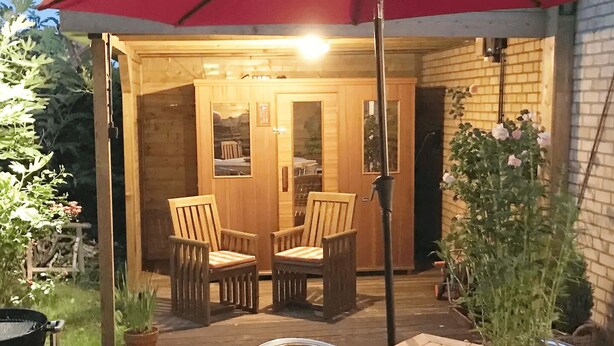 Un patio al aire libre con mobiliario de madera, incluyendo dos sillas y una mesa.