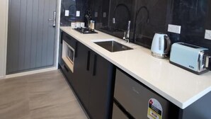 Una cocina moderna con puerta gris, armarios negros, encimera blanca y horno empotrado.