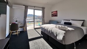 Habitación de hotel moderna con una cama grande, un escritorio, una silla y vistas al exterior.