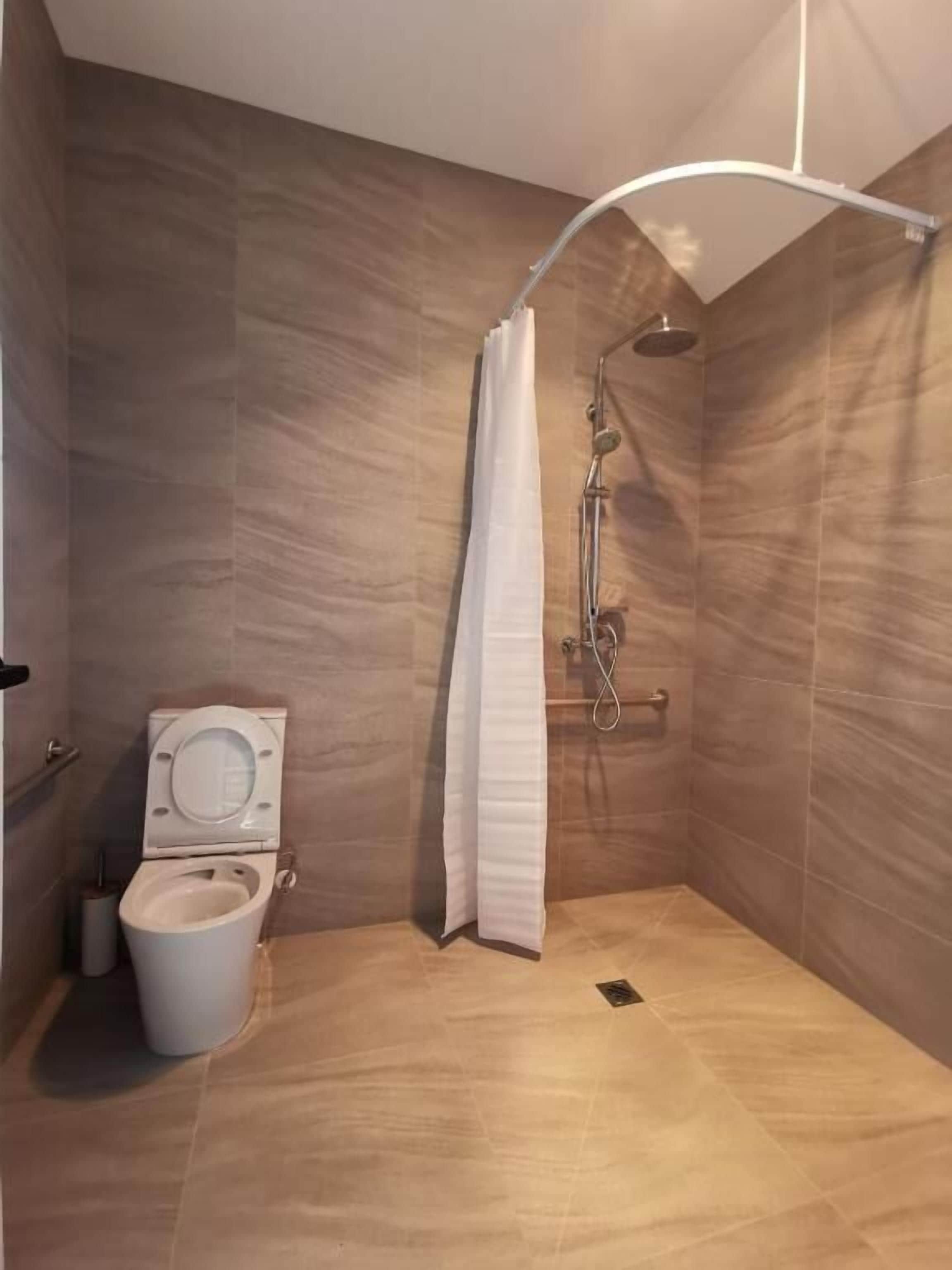 Een moderne badkamer met douche, toilet en een handdoekhouder.
