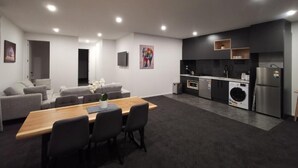 Un espacio moderno para vivir con comedor, sofá, cocina y electrodomésticos integrados.