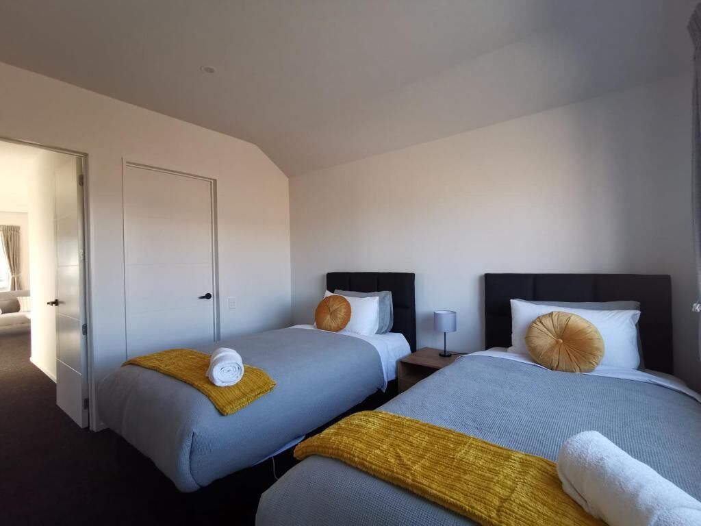 Une chambre d’hôtel avec deux lits, chacun doté d’une tête de lit, d’une table de chevet et d’une lampe.