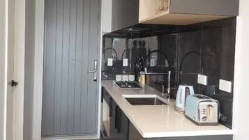 A modern kitchen with a grey door, black cabinets, a white countertop, and a toaster.