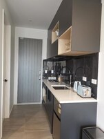 A modern kitchen with a grey door, black cabinets, a white countertop, and a toaster.