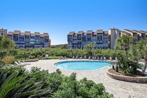 A modern hotel with a swimming pool surrounded by lush greenery and palm trees. - 1111 Beach Walker- Hosted by Moore AI Rentals (Fernandina Beach)