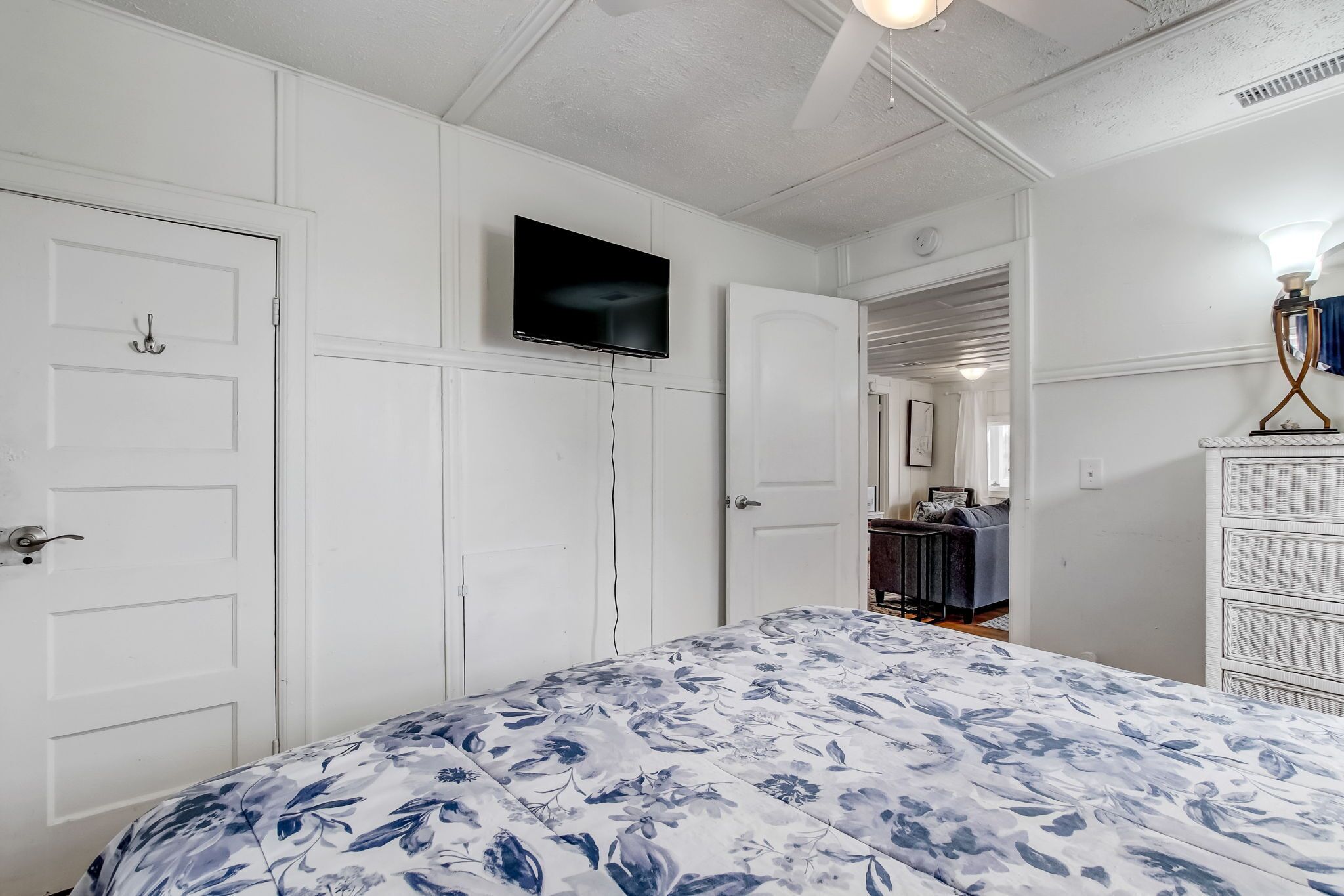 A bedroom with a bed, a television on the wall, and a dresser.