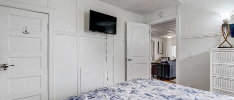 A bedroom with a bed, a television on the wall, and a dresser.