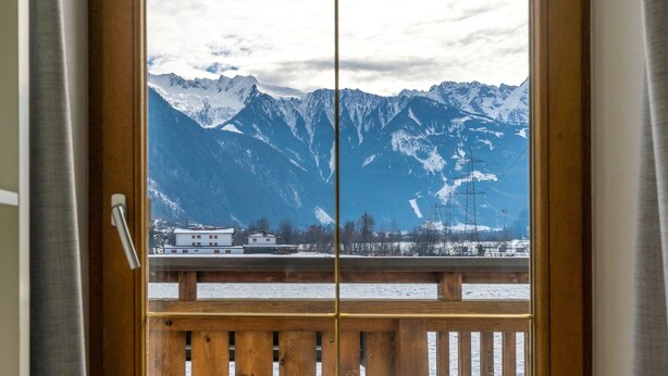 A view from a window with a wooden frame and a metal handle, overlooking a snowy mountain landscape with a few buildings in the foreground. - Apartment in Ramsau near Ski Slopes (Ramsau)