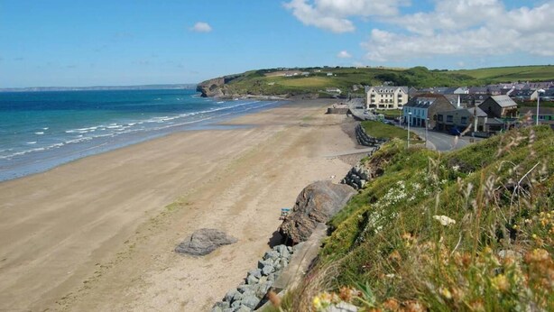 A coastal beach with a rocky shoreline, a clear blue sky, and buildings along the shore. - Beautiful 3-bed Cabin in Pembrokeshire Coast (Haverfordwest)