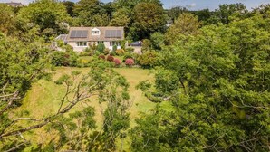 A house with solar panels, surrounded by lush greenery and trees. - Beautiful 3-bed Cabin in Pembrokeshire Coast (Haverfordwest)