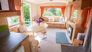 A cozy interior with a sofa set, a dining table, and a fireplace. - Beautiful 3-bed Cabin in Pembrokeshire Coast (Haverfordwest)