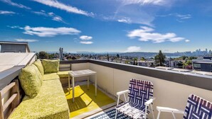 A rooftop terrace with a yellow floor, a green sofa, and patterned chairs. - 4313 Fremont · 3b2.5b Fremont Gem w/ Seattle Skyline & Lake View (Seattle)