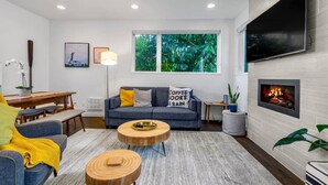 A modern living room with a grey sofa, wooden coffee table, and a fireplace. - 4313 Fremont · 3b2.5b Fremont Gem w/ Seattle Skyline & Lake View (Seattle)