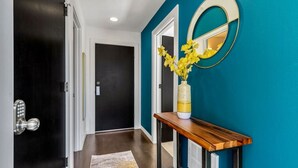 A hallway with a black door, a wooden console table with a vase of yellow flowers, and a mirror on the wall. - 4313 Fremont · 3b2.5b Fremont Gem w/ Seattle Skyline & Lake View (Seattle)