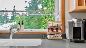 A kitchen counter with a sink, a coffee machine, and a shelf with packaged goods.