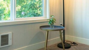 Una habitación con un gran ventanal, una lámpara de pie y una pequeña mesa con una planta.
