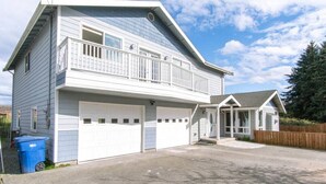 Ein zweistöckiges Haus mit Garage, überdachter Veranda und einem umzäunten Garten.