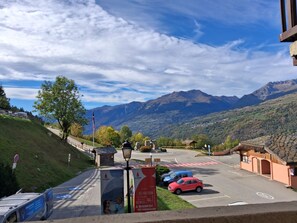 Ein Parkplatz mit Autos, Blick auf einen Berg und ein Gebäude mit traditionellem Dach.
