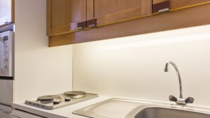 Una cocina con un lavamanos de acero inoxidable, una estufa empotrada y armarios de madera.