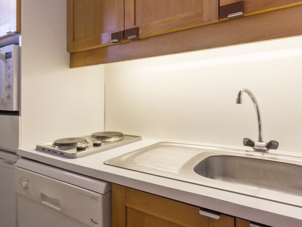 A kitchen with a stainless steel sink, a built-in stove, and wooden cabinets. - Cozy central studio, balcony, near slopes (La Plagne Montchavin Les Coches)