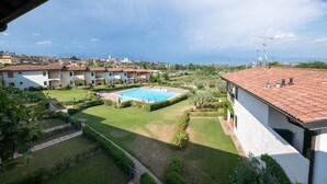 A residential area with a swimming pool surrounded by well-maintained lawns and hedges. - Appartamento Katy (Polpenazze del Garda)