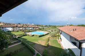 A residential area with a swimming pool surrounded by well-maintained lawns and hedges. - Appartamento Katy (Polpenazze del Garda)