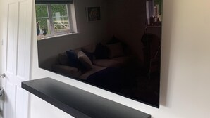 Una habitación con ventana, una puerta blanca y un estante negro.