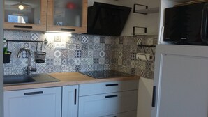 A kitchen with patterned tiles, a black microwave, and white cabinets. - Studio cabin 27 sqm, 4 people, pets allowed, balcony (Orcières Merlette)