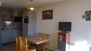A compact kitchen with a dining area, a ceiling fan, and a flat-screen TV on a stand. - Studio cabin 27 sqm, 4 people, pets allowed, balcony (Orcières Merlette)