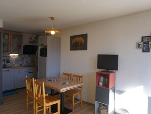 A compact kitchen with a dining area, a ceiling fan, and a flat-screen TV on a stand. - Studio cabin 27 sqm, 4 people, pets allowed, balcony (Orcières Merlette)