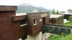 A modern building with a sign reading "LES PINEURS" and a mountain in the background. - Studio cabin 27 sqm, 4 people, pets allowed, balcony (Orcières Merlette)