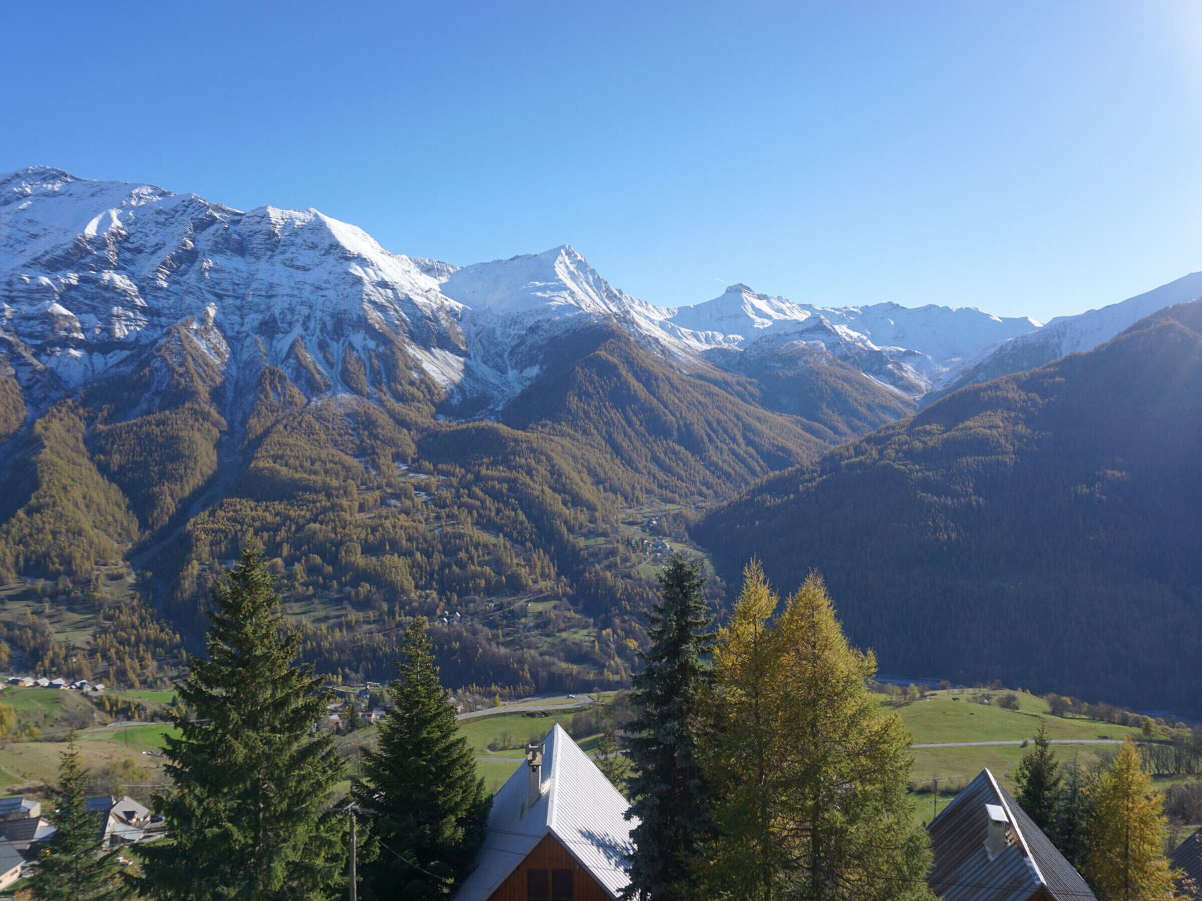 Eine Berglandschaft mit schneebedeckten Gipfeln und einem Tal mit Häusern.