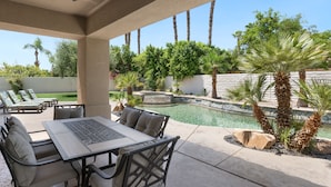An outdoor patio with a pool, lounge chairs, and a table. - It's A Mirage - Victoria Falls Home (Rancho Mirage)