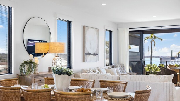 A modern living room with a dining area, featuring wicker furniture, a large mirror, and a view of the ocean. - Echoes Luxury Residence, Pet Friendly Walk to Cafes (Woolgoolga)