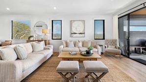 A modern living room with a sofa, armchairs, a coffee table, and a rug. - Echoes Luxury Residence, Pet Friendly Walk to Cafes (Woolgoolga)
