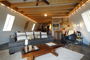 A cozy living room with a grey sofa, wooden coffee table, and a staircase leading to an upper level.