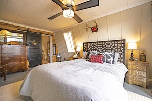 A bedroom with a bed, dresser, nightstands, and a ceiling fan.