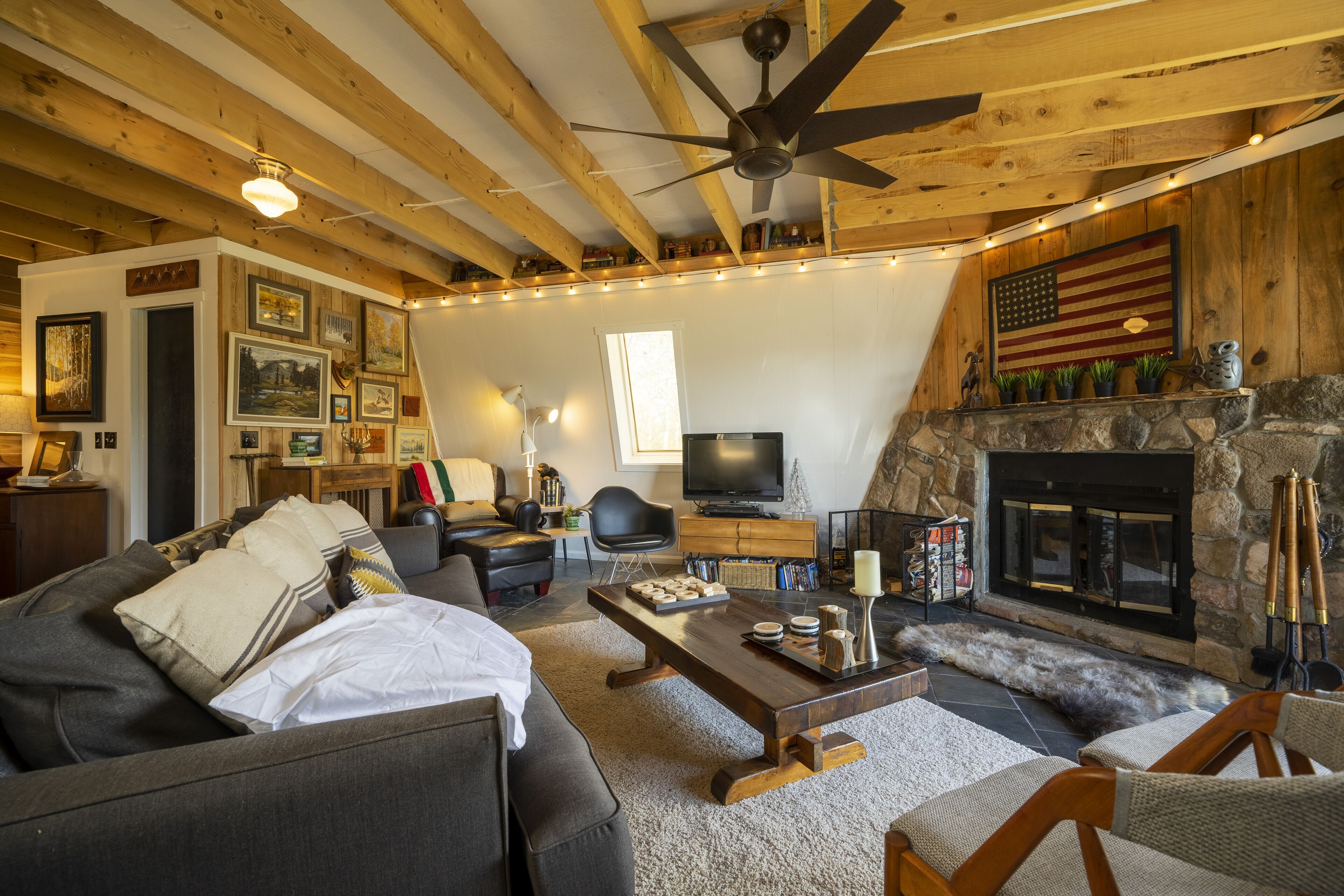 Ein gemütliches Wohnzimmer mit Kamin, Holzbalken und Fernseher.