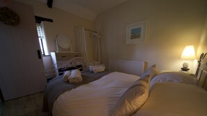 Un dormitorio con cama, mesita de noche con lámpara, cómoda, espejo y radiador.