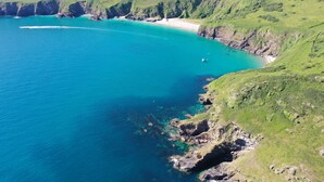 Un paisaje costero con vista despejada al mar, colinas verdes y una playa.