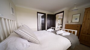 Un dormitorio con cama, cómoda, espejo y puerta que da a otra habitación.