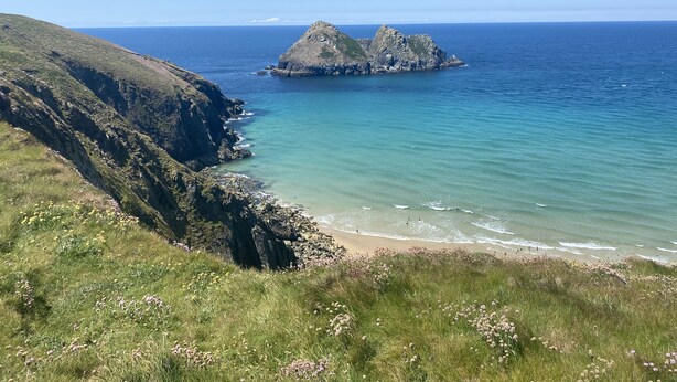 Un paisaje costero con un promontorio rocoso y mar azul cristalino.