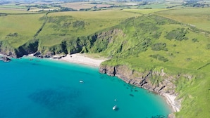 Vista aérea de una zona costera con playa, acantilados y aguas turquesas cristalinas.