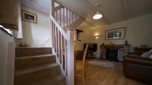Una escalera conduce a un dormitorio entrepiso, con chimenea, un sofá de cuero y un comedor con suelo de madera.