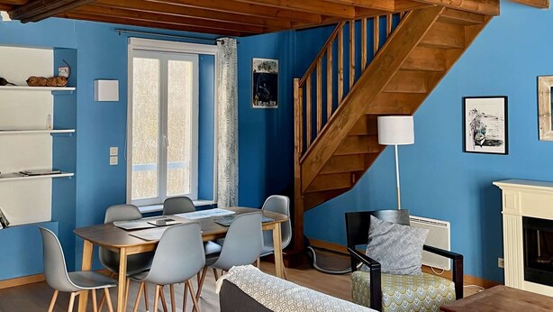 A spacious living area with a wooden staircase, a dining table with chairs, and a sofa. - L'hippocampe - Appt Mezzanine Centre D'arromanches (Arromanches-les-Bains)
