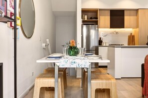 A modern kitchen with a stainless steel refrigerator, wooden cabinets, and a white countertop.
