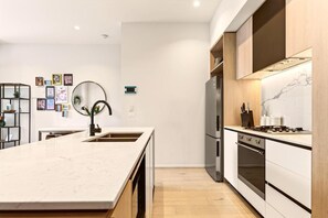 A modern kitchen with a marble countertop, stainless steel appliances, and wooden cabinetry.