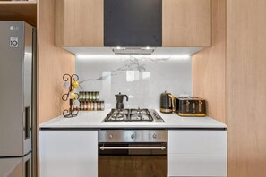 Kitchen equipped with a refrigerator, stove, and dishwasher, featuring a range hood above the cooking area.