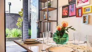Uma mesa de jantar posta com pratos, copos e um vaso de flores.