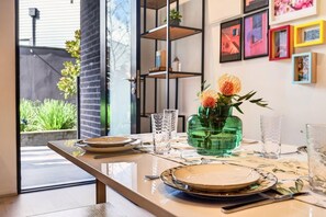A dining table set with plates, glasses, and a vase with flowers.